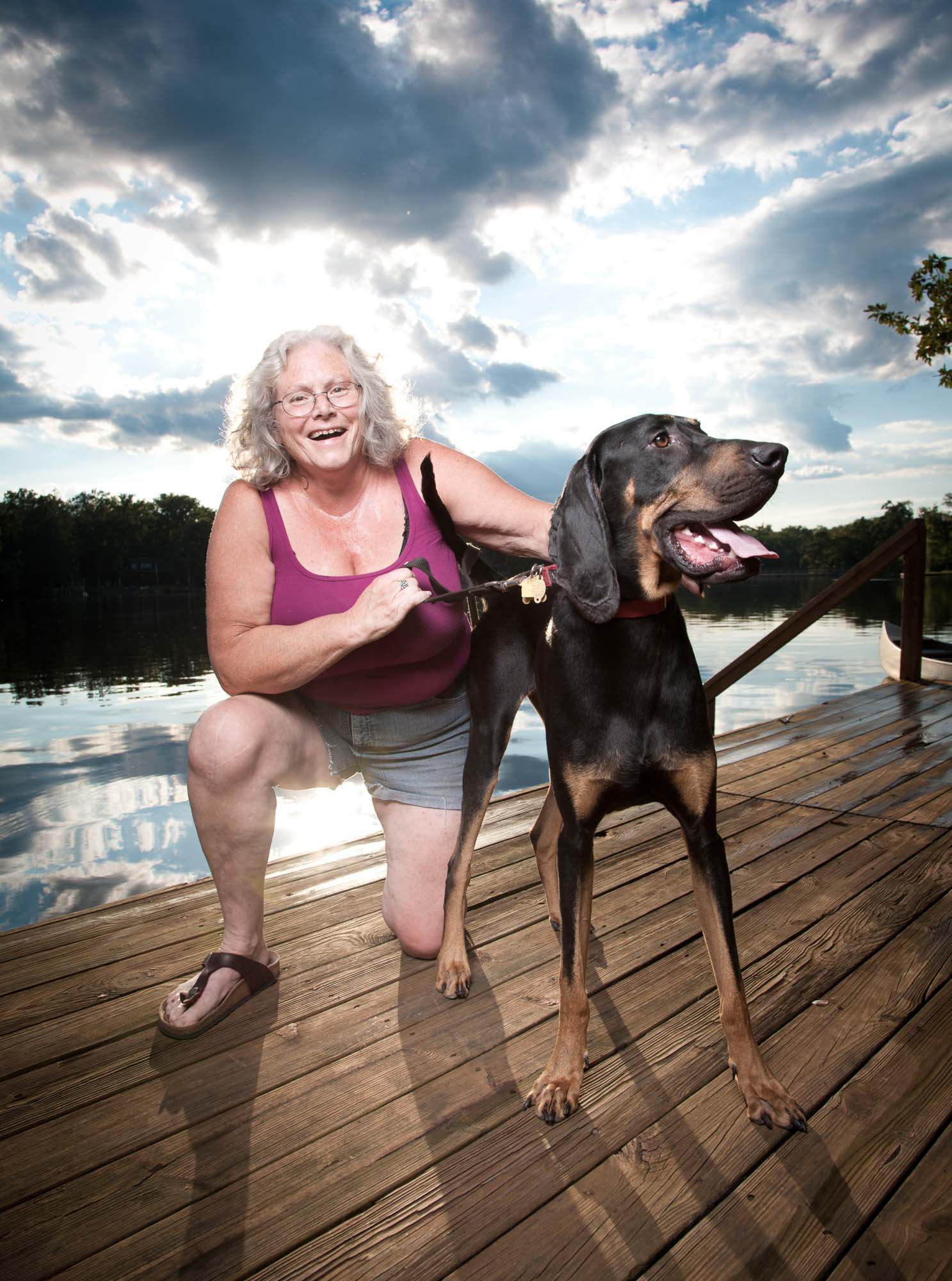 Active senior citizen posing with her pet on a dock at the lake