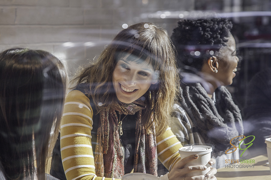 Mixed Race Group sitting in Café smiling at each other and having a discussion.